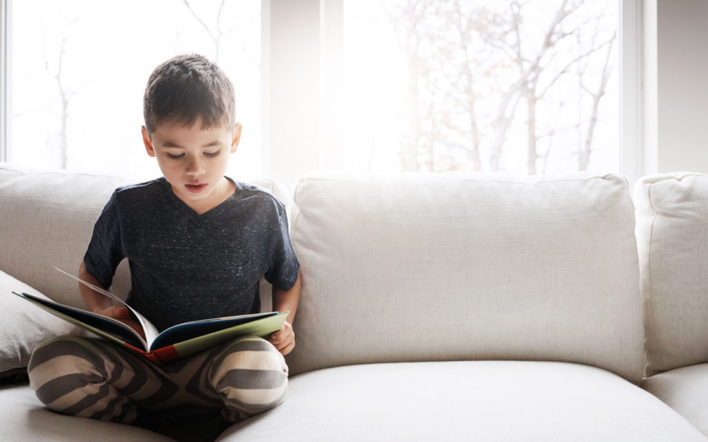 Child reading a book on the couch