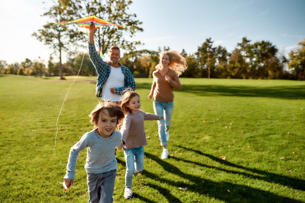 Family of four flying a kite at a park