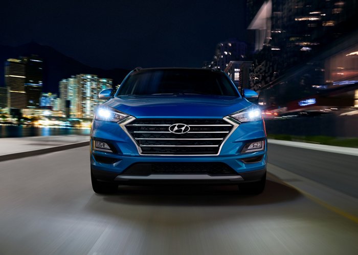 Front grille of a blue 2020 Hyundai Tucson on a highway at night