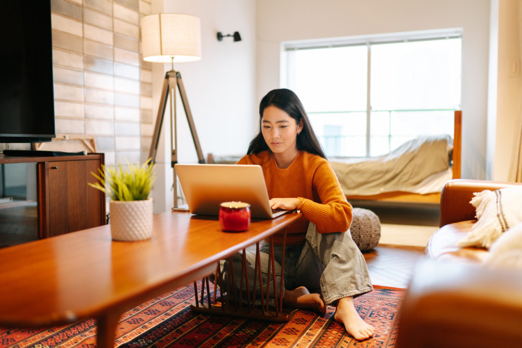 Young woman using laptop comfortably at home.