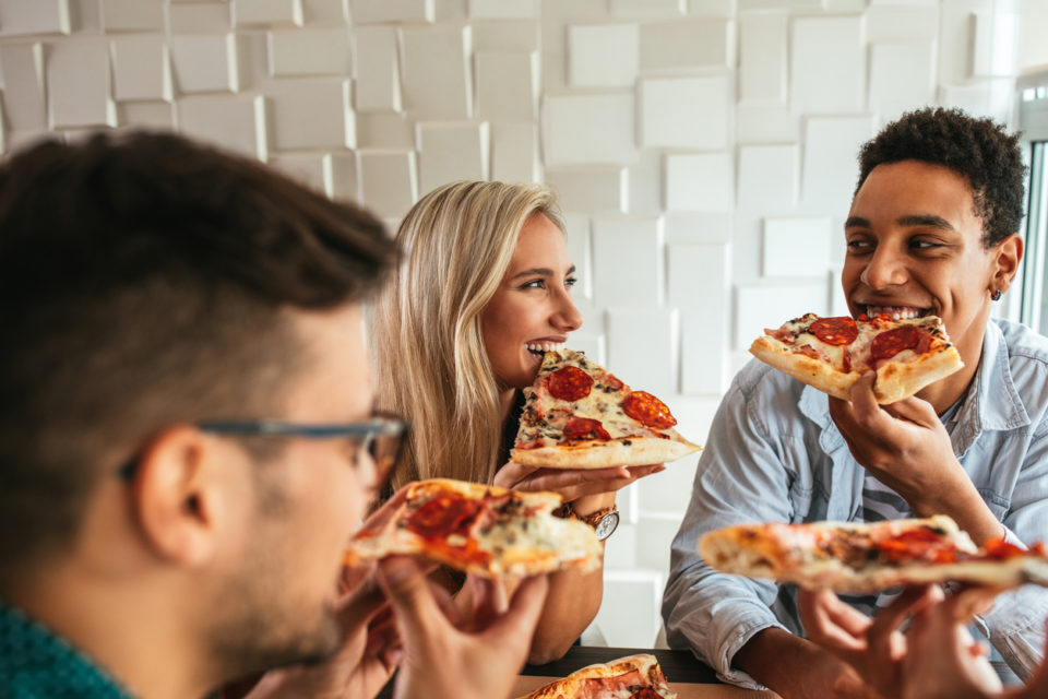Happy group of friends eating pizza