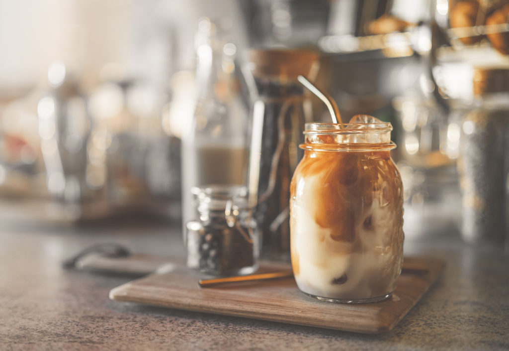 A woman is making iced coffee at home in the kitchen during the day.