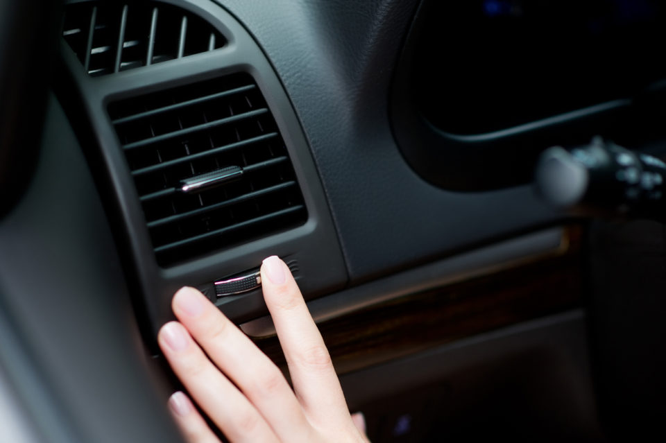 Driver adjusting air vent in car