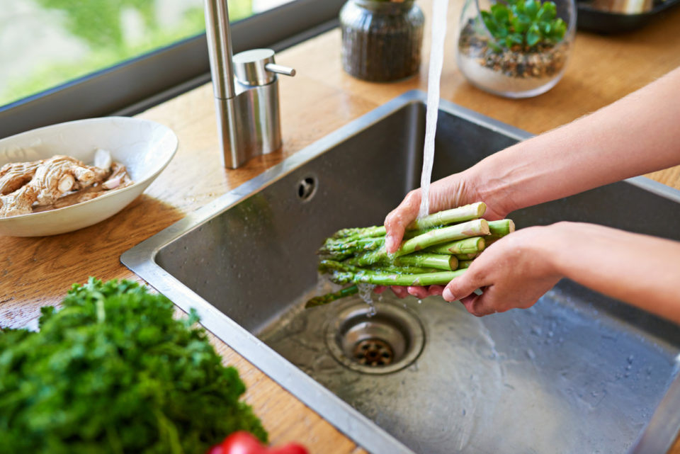 Cropped shot of a woman washing vegetables in a kitchen sink