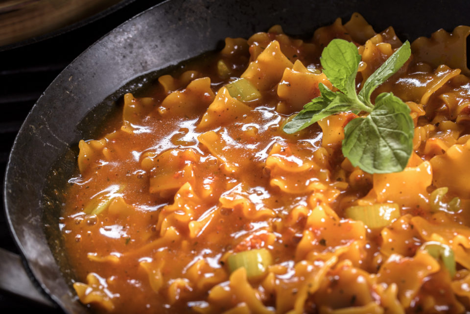 lasagna in a skillet with green herb garnish