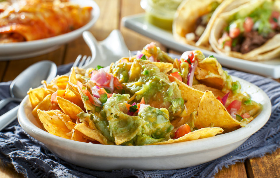 plate of nachos with guacamole and salsa close up