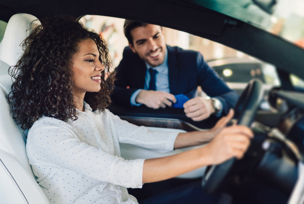 Smiling woman in the showroom enjoying luxury car