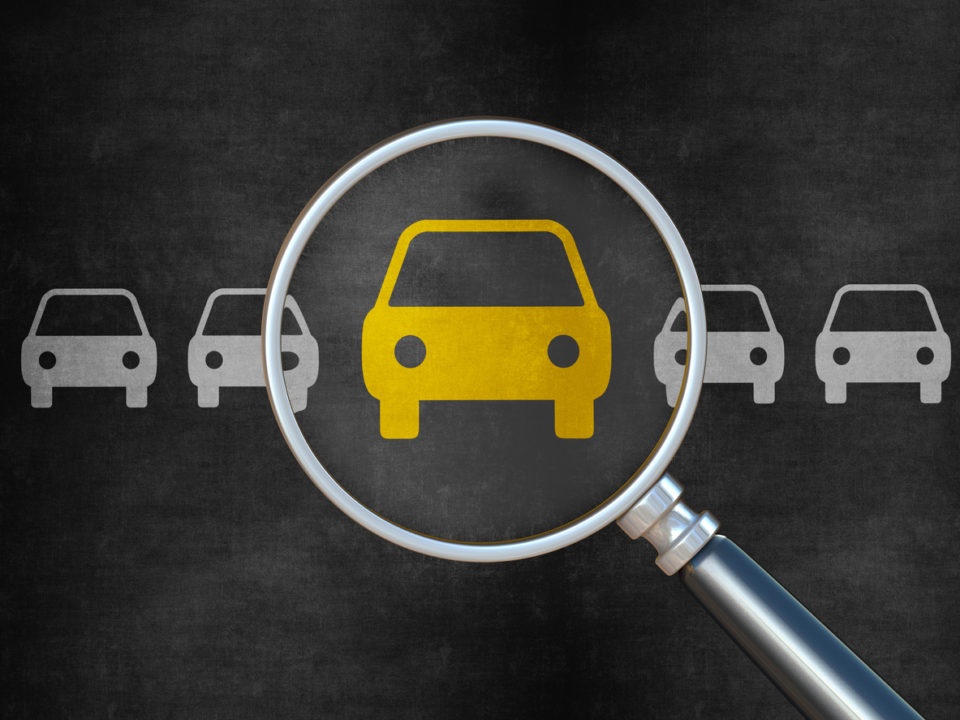illustration of magnifying glass over yellow car in row of grey cars