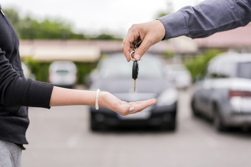 people on car lot handing over keys for a trade-in