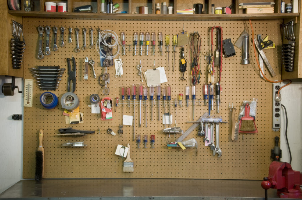 A wooden peg baord with tools organized by size and usage